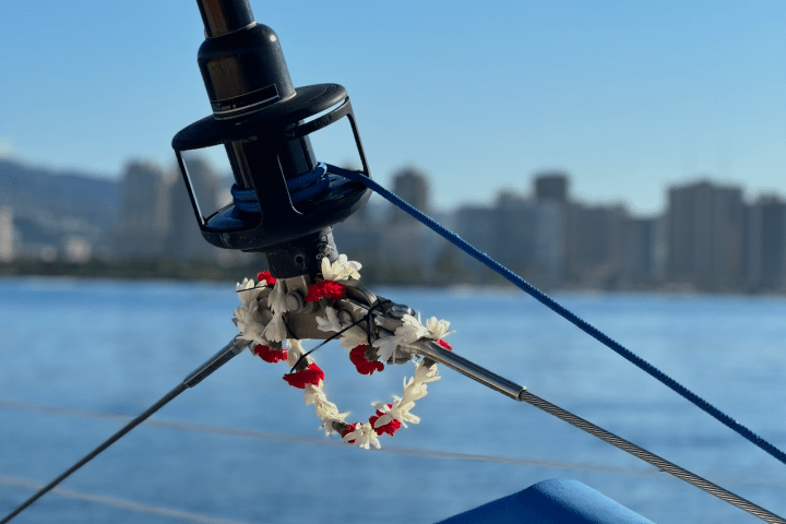 Flower lei on sailboat rope with city skyline in background.